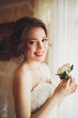 Beyaz elbiseli lüks gelin düğün törenine hazırlanırken poz veriyor.