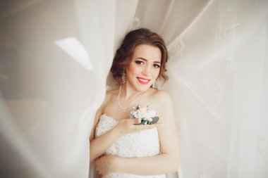 Beyaz elbiseli lüks gelin düğün törenine hazırlanırken poz veriyor.