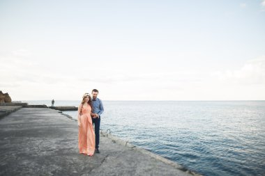 Güzel sevgi dolu çift, gurur iskelede yürüyüş uzun elbise ile