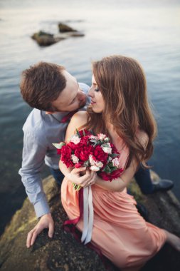 Mavi Denizi çevresinde büyük bir taş üzerinde oturan Düğün çifti