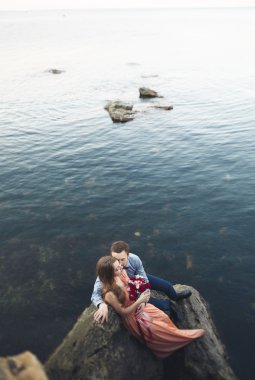 Mavi Denizi çevresinde büyük bir taş üzerinde oturan Düğün çifti