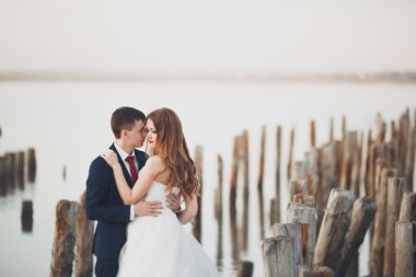 Güzel genç düğün çift, gelin ve damat arka plan denizde ahşap direklerin yakın poz