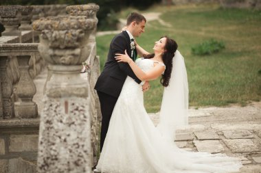 Güzel, romantik bir düğün. Yeni evliler. Eski kalenin yakınlarında sarılıyorlar.