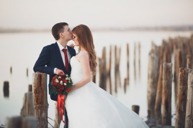 Çift düğün, damat, gelin buketi günbatımı üzerinde denize yakın poz ile