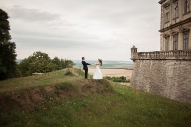 Güzel, romantik bir düğün. Yeni evliler. Eski kalenin yakınlarında sarılıyorlar.