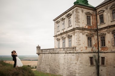 Güzel, romantik bir düğün. Yeni evliler. Eski kalenin yakınlarında sarılıyorlar.