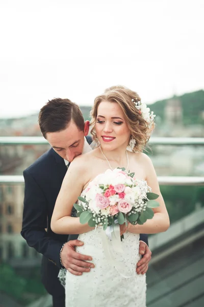 Gyönyörű pár, a menyasszony és a vőlegény pózol a régi város backgrounf erkéllyel — Stock Fotó