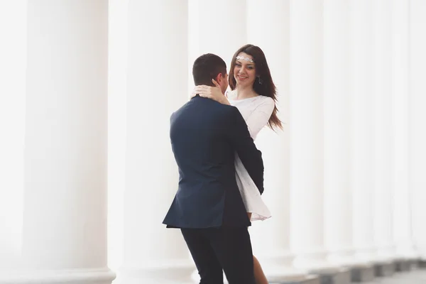 Beautiful couple, bride and groom posing near big white column — Stock Photo, Image