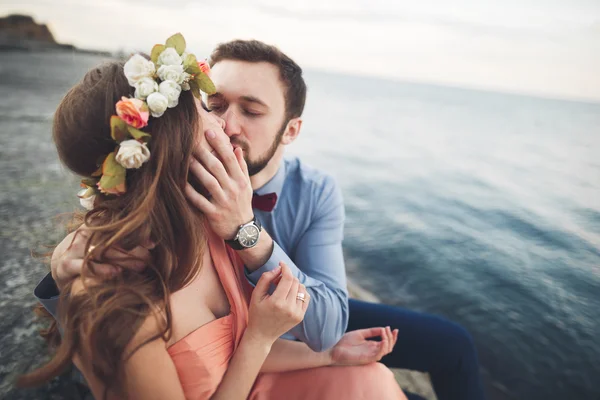 Pareja de boda sentada en piedra grande alrededor del mar azul — Foto de Stock