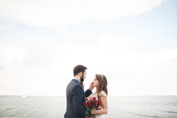 Séta a tengerparton naplementekor, nászutas esküvői pár. — Stock Fotó
