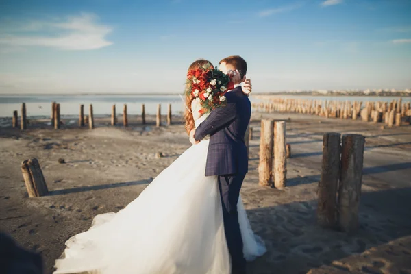 Elegante pareja de boda feliz elegante, novia, magnífico novio en el fondo del mar y el cielo — Foto de Stock