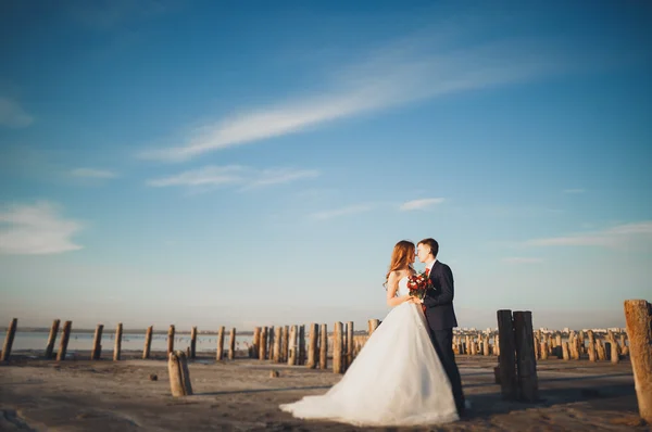 Elegáns elegáns boldog esküvő pár, menyasszony, gyönyörű vőlegény a háttérben a tenger és az ég — Stock Fotó