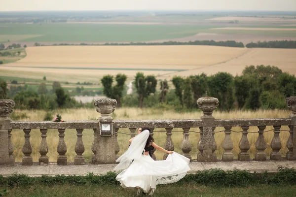 Feliz casamento casal abraçando e beijando no fundo velho castelo — Fotografia de Stock