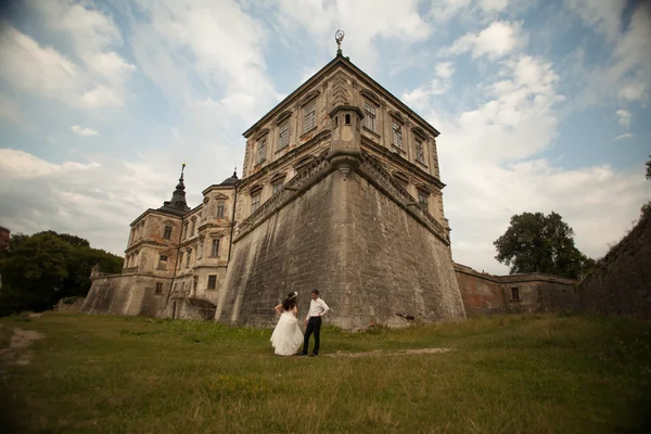 Счастливая свадебная пара обнимает и целует на заднем плане старый замок — стоковое фото
