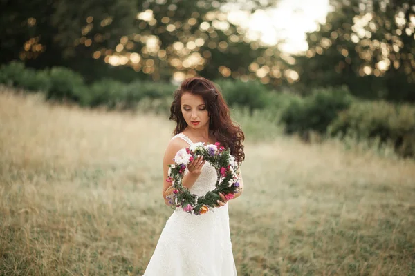 Mariée. Belle jeune femme blonde dans le parc avec couronne de fleurs et bouquet par une chaude journée d'été — Photo