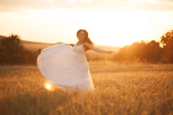 Feliz bela noiva jovem lá fora em um prado de verão no pôr do sol — Fotografia de Stock