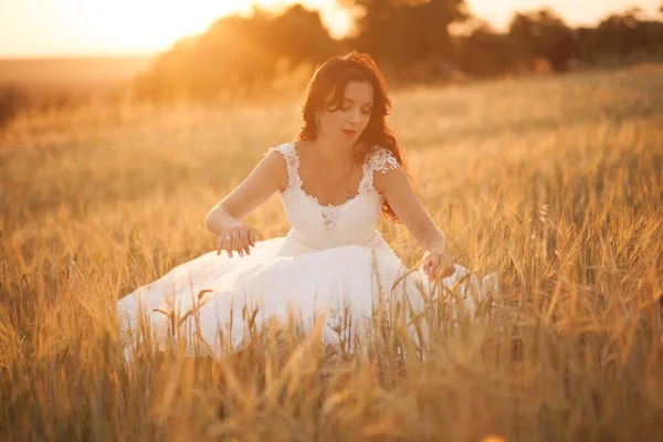 Feliz bela noiva jovem lá fora em um prado de verão no pôr do sol — Fotografia de Stock