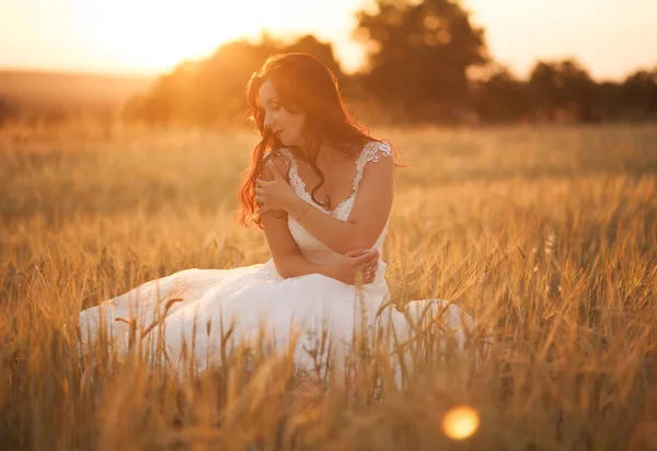 Feliz bela noiva jovem lá fora em um prado de verão no pôr do sol — Fotografia de Stock