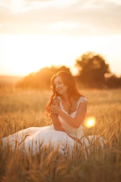 Feliz bela noiva jovem lá fora em um prado de verão no pôr do sol — Fotografia de Stock