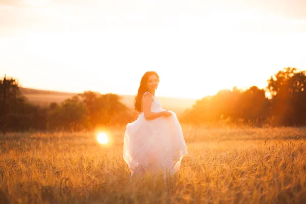 Feliz bela noiva jovem lá fora em um prado de verão no pôr do sol — Fotografia de Stock