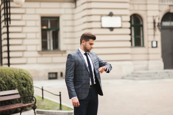 Hombre de negocios confiado mirando su reloj de pulsera en traje —  Fotos de Stock