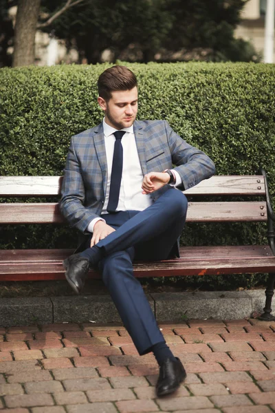 Hombre de negocios confiado mirando su reloj de pulsera en traje —  Fotos de Stock