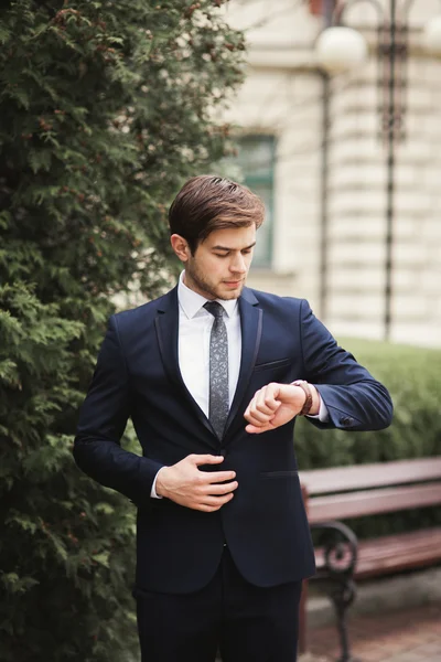 Selbstbewusster Geschäftsmann blickt im Anzug auf seine Armbanduhr — Stockfoto