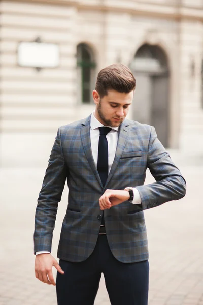 Selbstbewusster Geschäftsmann blickt im Anzug auf seine Armbanduhr — Stockfoto