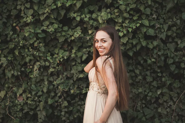 Hermosa chica, modelo cerca de la pared de hojas y arbustos en el parque —  Fotos de Stock