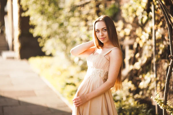 Atractiva joven con vestido largo disfrutando de su tiempo al aire libre en el fondo del atardecer del parque —  Fotos de Stock