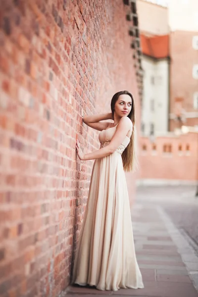 Piękna sexy dziewczyna z długimi włosami i strój idealny kształt, opalone ciała possing w pobliżu ściany — Zdjęcie stockowe