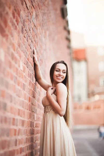 Hermosa chica sexy con el pelo largo y vestido de la forma perfecta cuerpo bronceado possing cerca de la pared —  Fotos de Stock