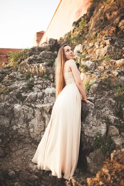 Atractiva joven en vestido largo de pie sobre las rocas — Foto de Stock