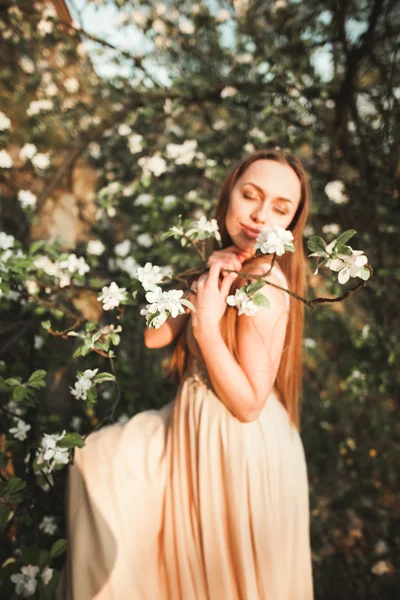 Młoda piękna dziewczyna w długiej sukni i Wieniec kwiatów, w pobliżu ogrodu krzew bzu — Zdjęcie stockowe