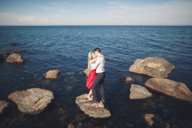 Deniz, mavi gökyüzü yakınındaki taş poz romantik sevgi dolu Çift