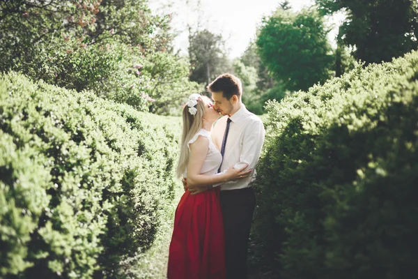 Joven hermosa pareja besándose y abrazándose cerca de los árboles con flor en el parque de verano —  Fotos de Stock