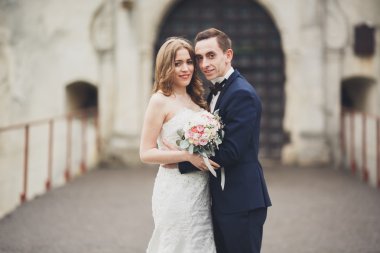 Güzel, romantik bir düğün. Yeni evliler. Eski kalenin yakınlarında sarılıyorlar.