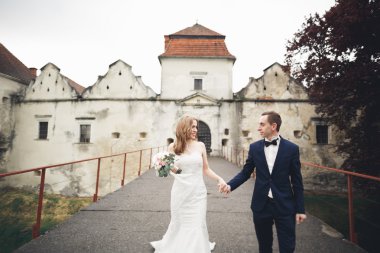 Güzel, romantik bir düğün. Yeni evliler. Eski kalenin yakınlarında sarılıyorlar.