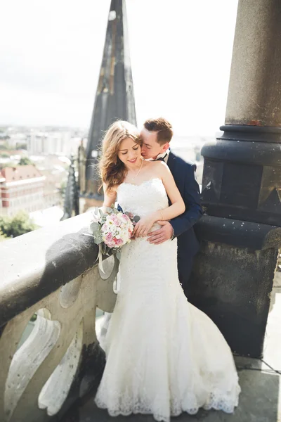 Stylový krásný svatební pár líbání a objímání na pozadí panoramatický výhled na staré město — Stock fotografie
