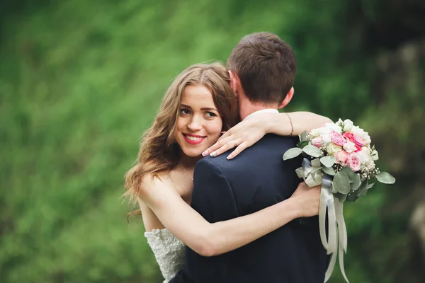 Cheerful married wedding couple posing nea rocks — Stock Photo, Image