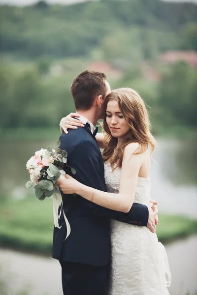 Casal de casamento lindo beijando e abraçando perto do lago com a ilha — Fotografia de Stock