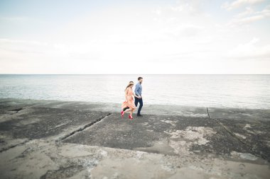 Güzel sevgi dolu çift, gurur iskelede yürüyüş uzun elbise ile