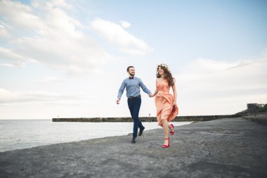 Güzel sevgi dolu çift, gurur iskelede yürüyüş uzun elbise ile