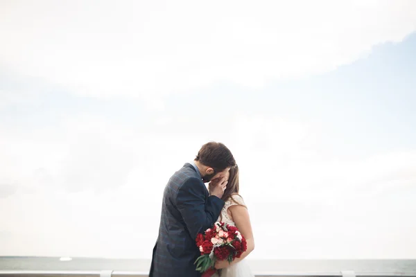 Casamento casal em pé em um cais sobre o mar — Fotografia de Stock