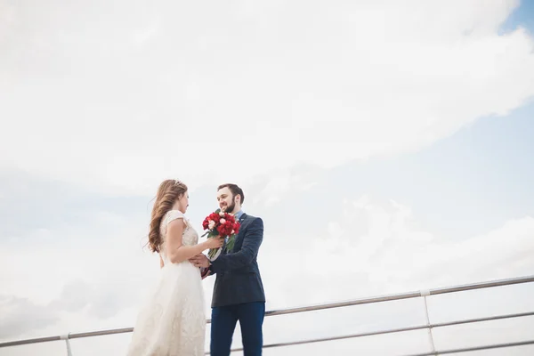 Pareja de recién casados caminando en la playa al atardecer . — Foto de Stock