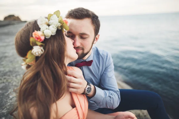 Matrimonio coppia seduta su una grande pietra intorno al mare blu — Foto Stock