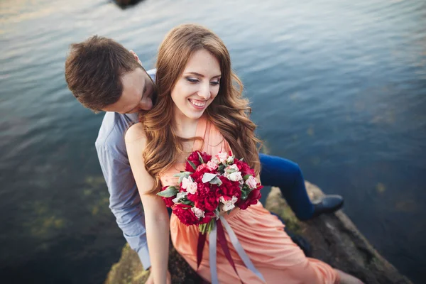 Matrimonio coppia seduta su una grande pietra intorno al mare blu — Foto Stock