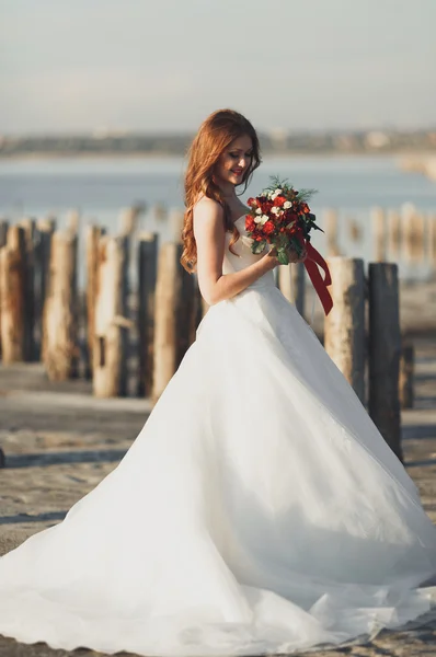 Hermosa novia joven con ramo de novia posando en el mar de fondo —  Fotos de Stock