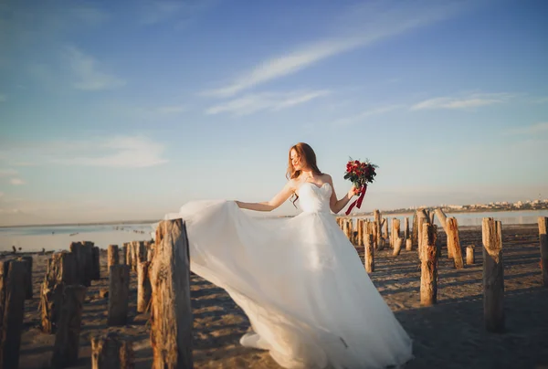 Όμορφη νεαρή νύφη με νυφική ανθοδέσμη που παρουσιάζουν στη θάλασσα φόντο — Φωτογραφία Αρχείου