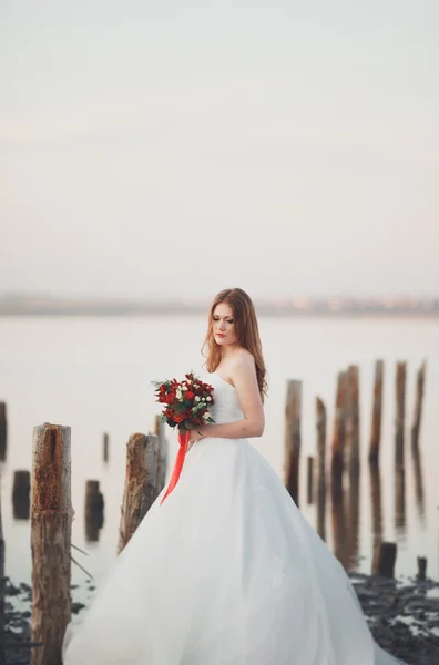 白いドレスの背景海と木の棒でポーズでロマンチックな美しい花嫁 — ストック写真